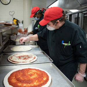 Chefs make pizzas.